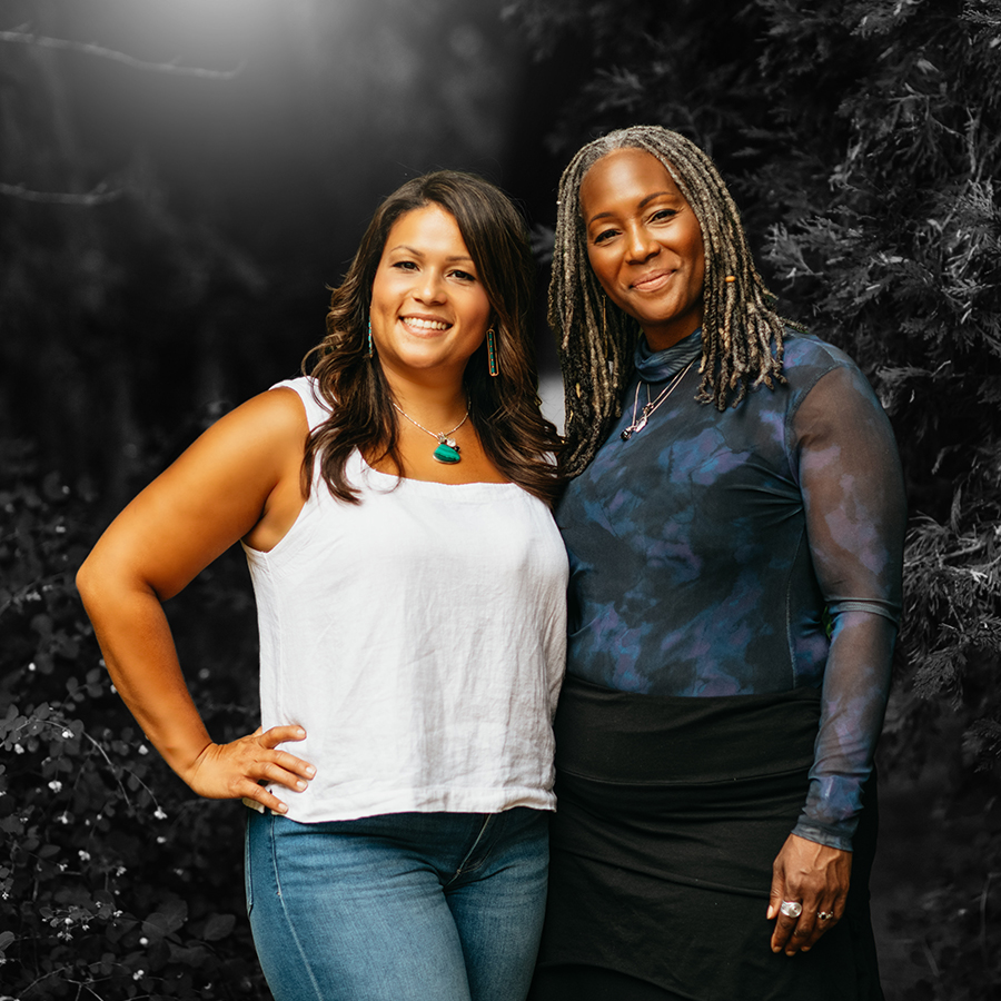 A & T Two women standing with their arms crossed smiling backed against a bush. About US FieldWise Marketing