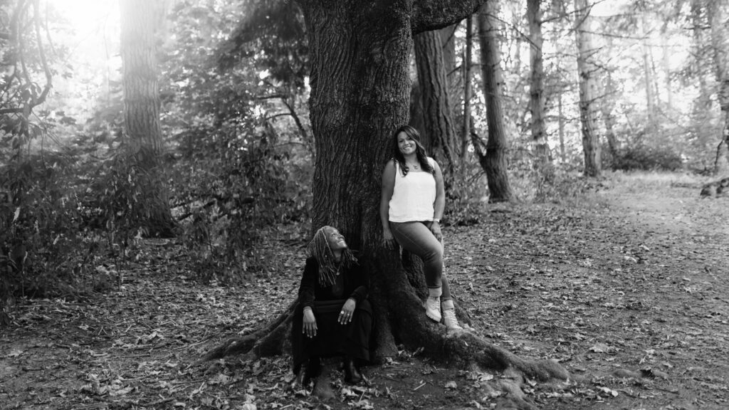 Image of two women sitting next to a tree smiling at each other_FieldWise Marketing Group About Us