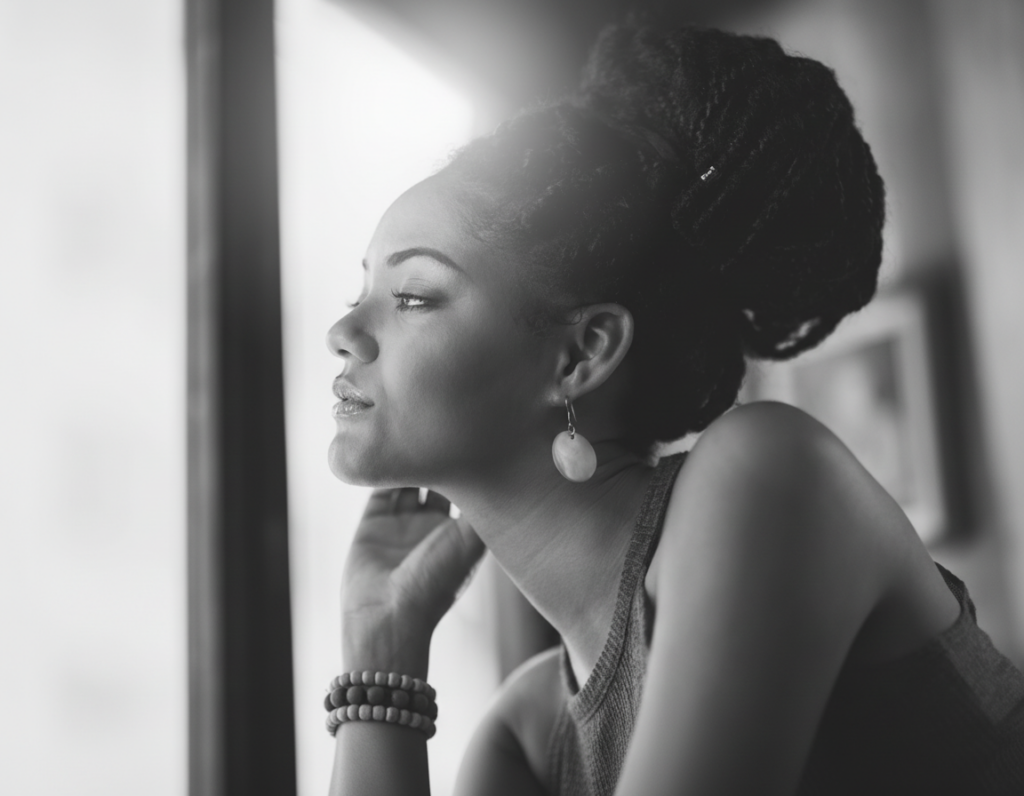 Black woman at a coffee shop looking out the window in contemplation