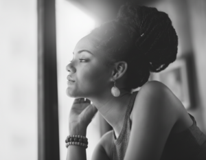 Black woman at a coffee shop looking out the window in contemplation