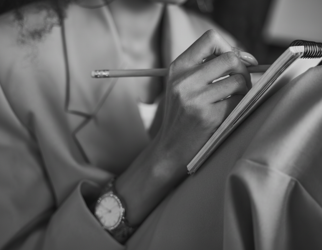image of a woman sitting cross legged writing on a tablet.
