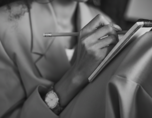 image of a woman sitting cross legged writing on a tablet.