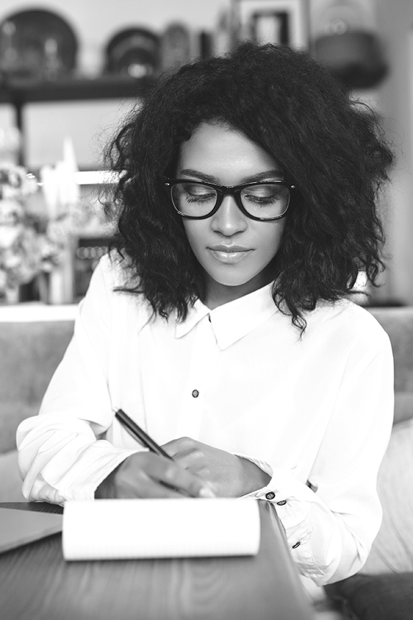 black woman taking notes sitting in a cafe_FieldWise Marketing Group