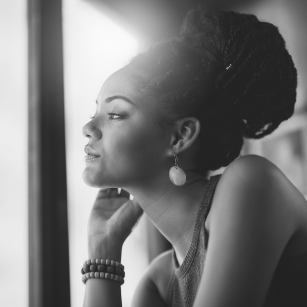Black woman at a coffee shop looking out the window in contemplation